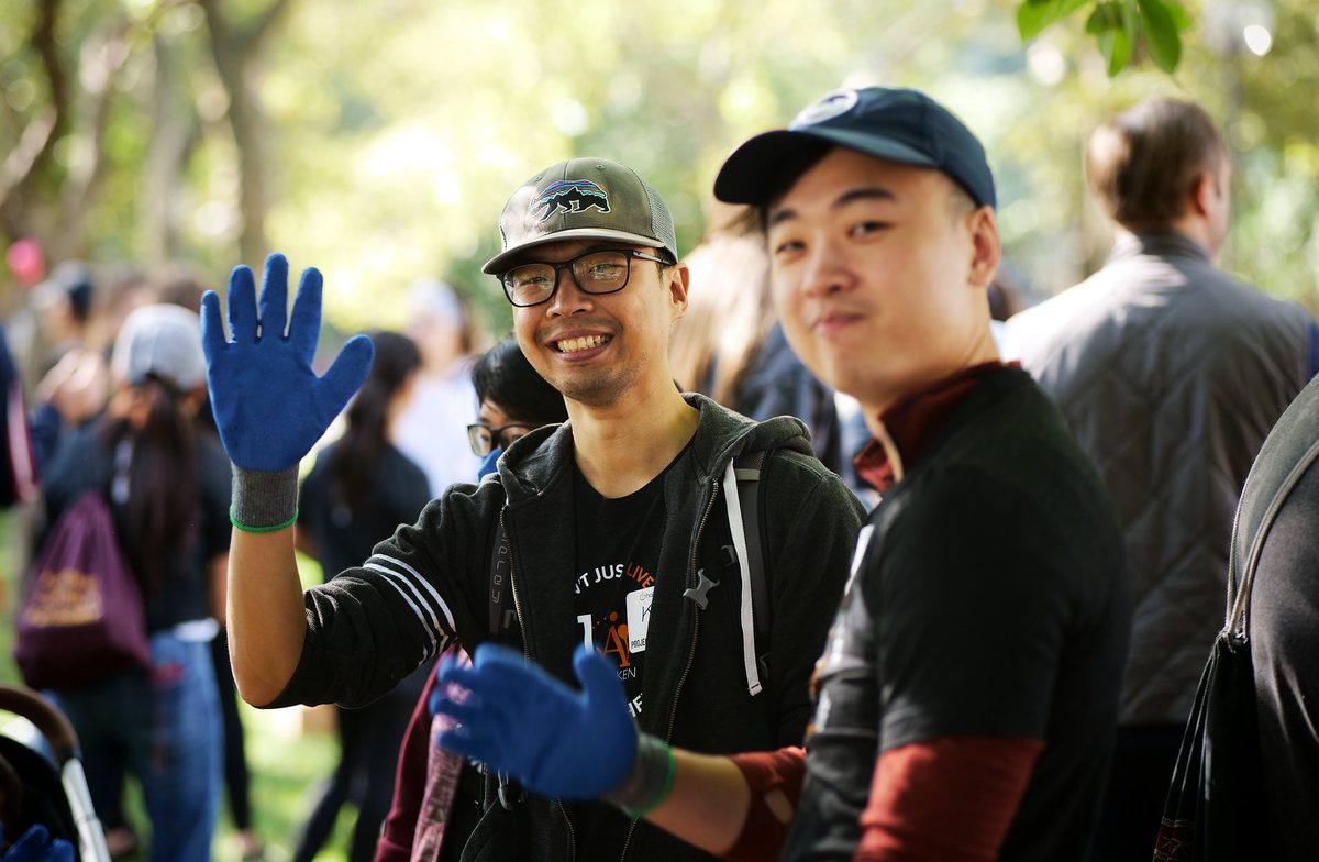 A 1Day volunteer in work gloves smiling and waving