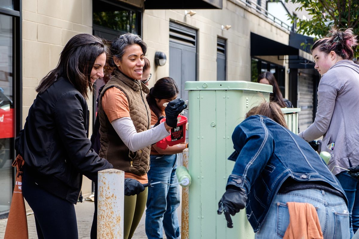 Volunteers repainting a utility box on a Hoboken street